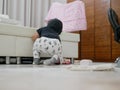 Little Asian baby girl cleaning her own mess, body powder, on the house floor