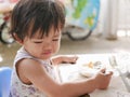 Little Asian baby girl enjoys eating food by herself Royalty Free Stock Photo