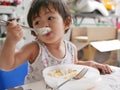 Little Asian baby girl enjoys eating food by herself Royalty Free Stock Photo