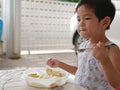 Little Asian baby girl enjoys eating food by herself Royalty Free Stock Photo