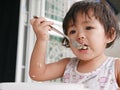 Little Asian baby girl enjoys eating food by herself Royalty Free Stock Photo