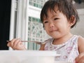 Little Asian baby girl enjoys eating food by herself Royalty Free Stock Photo