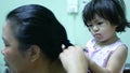 Little Asian baby girl giving her aunty`s hairs done - child development through learning to do things for others
