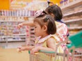 Little Asian baby girl having fun standing in a shopping cart with her sister while her mother does a shopping Royalty Free Stock Photo