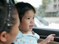 Little Asian baby girl having fun traveling with her mother by car as she learning to tell what she see during the trip