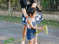 Little Asian baby girl, with help from her mother, getting ready to play Banana rib hobbyhorse riding Ma karn kluay