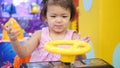 Little Asian baby girl holding a steering wheel of a driving-car arcade game and enjoyed pretending to drive it