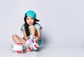 Little asian baby girl kid sitting with roller skates in light blue t-shirt and hat cap happy smiling on white Royalty Free Stock Photo