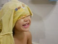 Little Asian baby girl laughing at herself in a mirror, playing / taking off a shirt before taking a shower Royalty Free Stock Photo