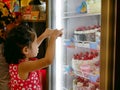 Little Asian baby girl looking and touching the bakery fridge as she was hungry for beautiful cakes