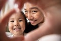 Little asian baby girl making heart gesture with smiling mom. Royalty Free Stock Photo