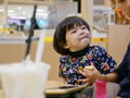 Little Asian baby girl enjoys having a piece of butter bread with whipped cream by herself at a shopping mall Royalty Free Stock Photo