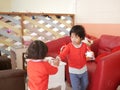 Little Asian baby girl giving / sharing a cup of ice cream to her younger sister