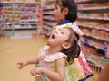 Little Asian baby girl having fun standing in a shopping cart with her sister in a supermarket Royalty Free Stock Photo
