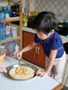 Little Asian baby girl spreding pizza sauce over a pizza dough Royalty Free Stock Photo