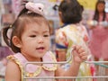 Little Asian baby girl standing in a cart waiting for her mother to do shopping at a supermarket Royalty Free Stock Photo