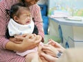 Little Asian baby girl, one year old, crying in pain while pediatric nurses securing her leg and giving her a vaccination Royalty Free Stock Photo