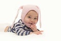Little Asian baby girl with pink rabbit hat and sucks fingers on white background