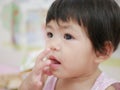 Little Asian baby girl putting her finger into her mouth Royalty Free Stock Photo