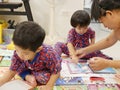 Little Asian baby girl right being taught by her mother to hold a color pen to do painting