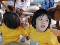 Little Asian baby girl sitting and playing / exploring with her younger sister under a dinning table at a restaurant Royalty Free Stock Photo