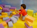 Little Asian baby girl stacking up foam building bricks / blocks at an indoor playground