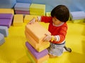 Little Asian baby girl stacking up foam building bricks / blocks at an indoor playground