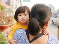 Little Asian baby girl, 2 years old, enjoys being carried by her auntie walking on the roadside