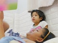 Little Asian baby girl, 3 years old, enjoys listening to her mother reading a bedtime story tale from a book
