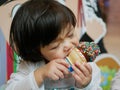 Little Asian baby girl, 2 years old, feeling blissful eating / biting ice cream cone Royalty Free Stock Photo