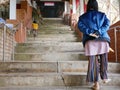 Asian baby girl learning to climb up the stairs by herself, while having her mother watching from a far distance Royalty Free Stock Photo