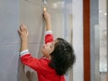 Little Asian baby girl, 3 years old, reaching her hand out to try pushing the elevator button Royalty Free Stock Photo