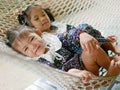 Little Asian baby girls the closer one enjoys lying down on a hammock with together with her older sister at home