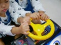 Little Asian baby girls, siblings, sharing a steering wheel of an arcade game