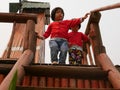 Little Asian baby girls, sisters, together going down stairs on their own while holding onto the railing