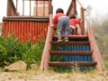 Little Asian baby girls, sisters, together going up stairs on their own while holding onto the railing