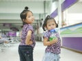 Little Asian baby girls, Thais, sisters, smiling and making cute pose together for indoor photo shoot