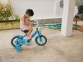 Little Asian baby learning to ride a bicycle with training wheels at home Royalty Free Stock Photo