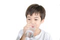 Little asian boy drinks water from a glass on white background