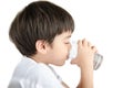 Little asian boy drinks water from a glass on white background