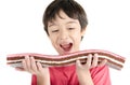 Little asian boy eating long cherry cake isolate on white background Royalty Free Stock Photo