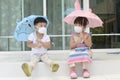 Little Asian boy and girl holding an umbrella and wearing face mask protection from coronavirus illnesses