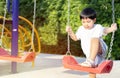 Little Asian boy having fun on a swing on the playground in public park on autumn day Royalty Free Stock Photo