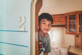 Little Asian Boy hiding behind a Caravan trailer home door waiting for parent to come home