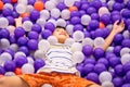 Little asian boy playing in ball pit playground with purple and white ball Royalty Free Stock Photo