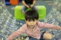A little Asian boy is playing with a giant, rolling ball with holes