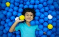 A little Asian boy is playing with a lot of blue and yellow balls Royalty Free Stock Photo