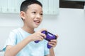 little Asian boy playing a video game. shot of a child holding a game controller. A kid is smiling and playing happily Royalty Free Stock Photo