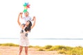 Little Asian boy riding back on his super power mom in meadow near lake. Mother and son playing together. Celebrating in Mother Royalty Free Stock Photo