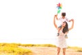 Little Asian boy riding back on his super power mom in meadow near lake. Mother and son playing together. Celebrating in Mother Royalty Free Stock Photo